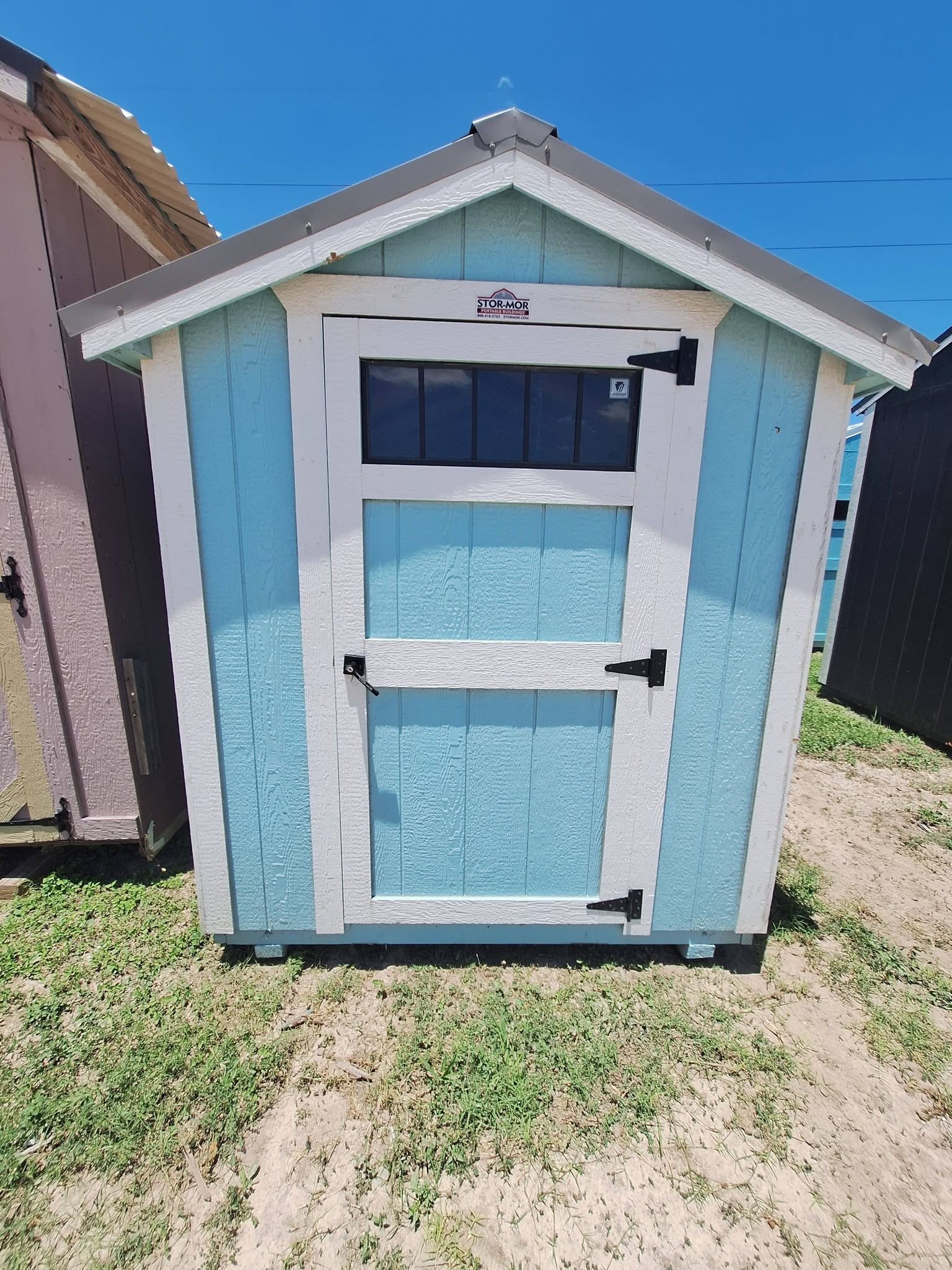 Painted cabin-style shed with a transom window in Alamo, TX