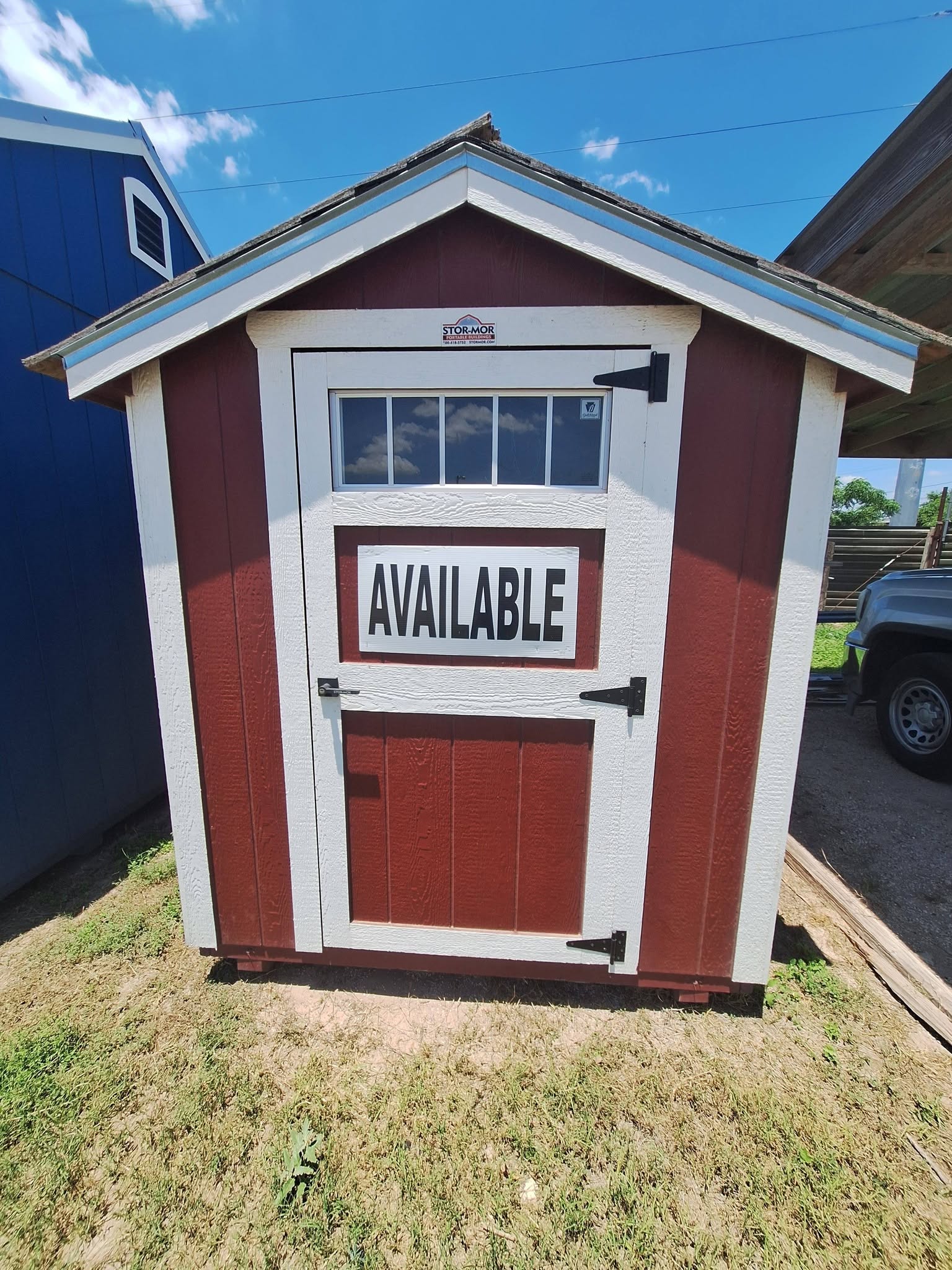 Red and white storage shed marked Available on the Alamo lot