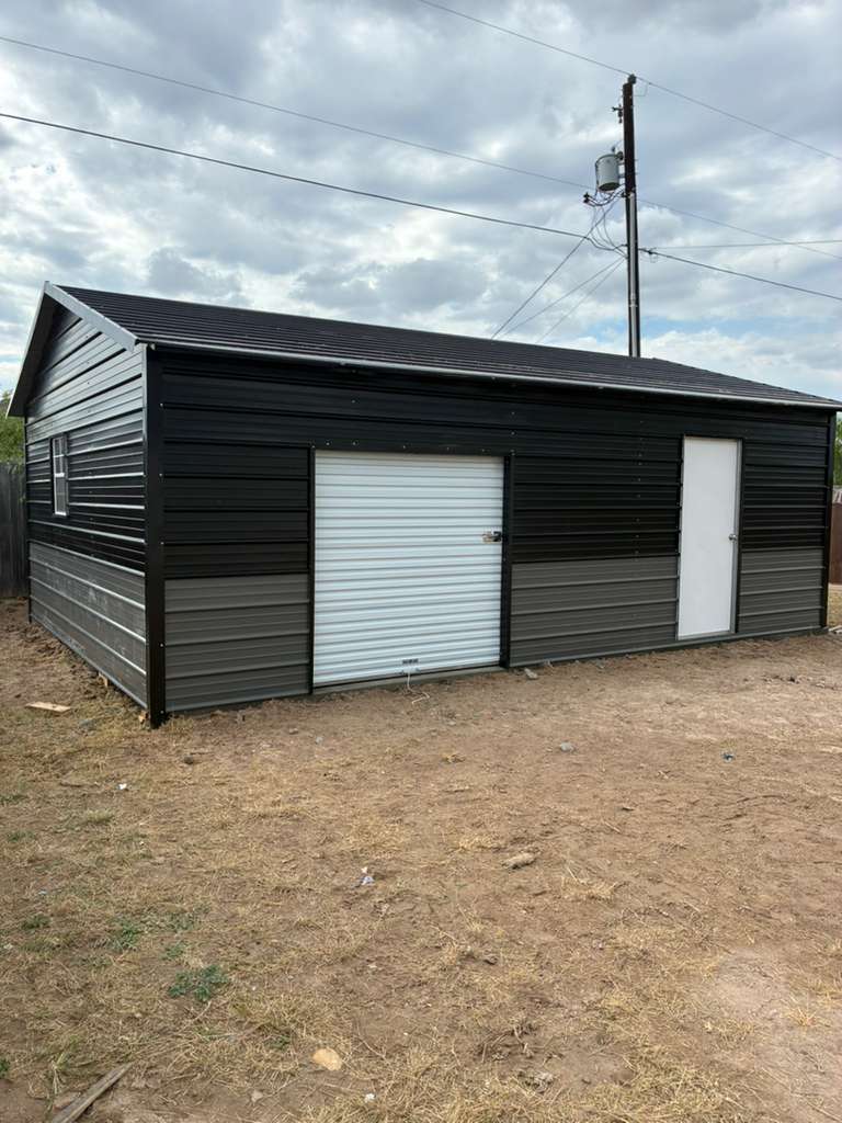 Black metal garage and workshop building with a roll-up door on the Mesquite Sheds & More lot in Alamo, TX