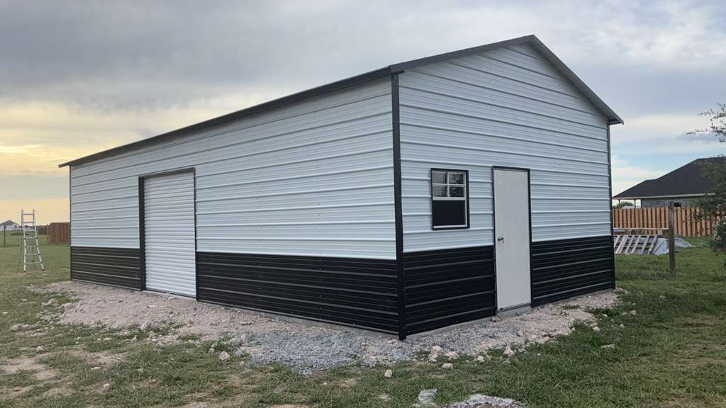 White and black metal garage building with a roll-up door on the Mesquite Sheds & More lot in Alamo, TX